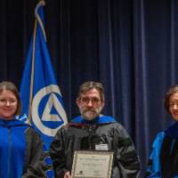 2 faculty and provost take picture on stage
